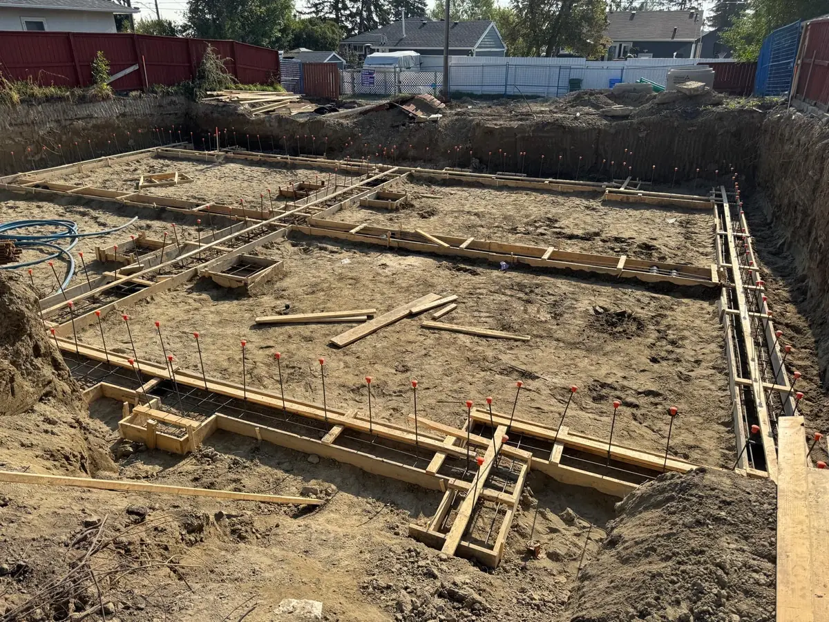 Foundation footing forms with rebar laid out in an excavated basement