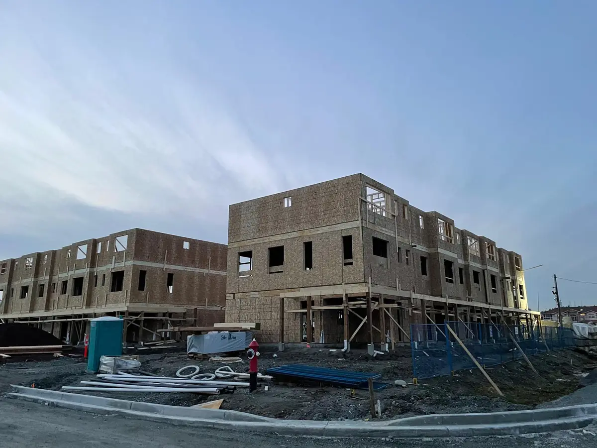 A row of multi-unit townhomes framed and sheathed at dusk